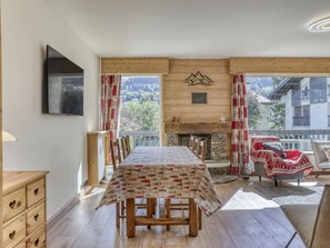 Ein Essbereich mit einem Tisch für vier Personen, einem Kamin, Holzwänden und Blick auf eine Berglandschaft.
