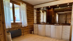 A modern kitchen with wooden cabinetry, a built-in oven, and a window with curtains. - Spacious apartment with south balcony - 7 guests (Villard-de-Lans)