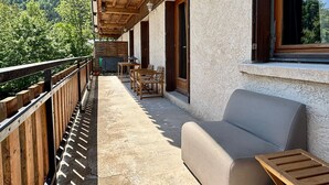 A balcony with wooden railings, a sofa, and a table. - Spacious apartment with south balcony - 7 guests (Villard-de-Lans)