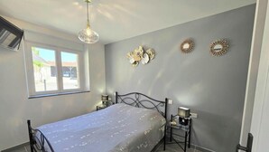 Ein Schlafzimmer mit Bett, Nachttischen, einer Pendelleuchte und Wanddekorationen.