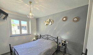 Ein Schlafzimmer mit Bett, Nachttischen, einer Pendelleuchte und Wanddekorationen.