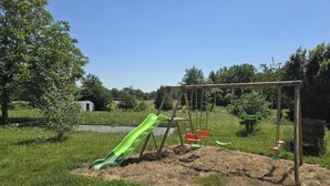 Ein Spielplatz mit Rutsche, Schaukeln und einer Schaukelanlage.