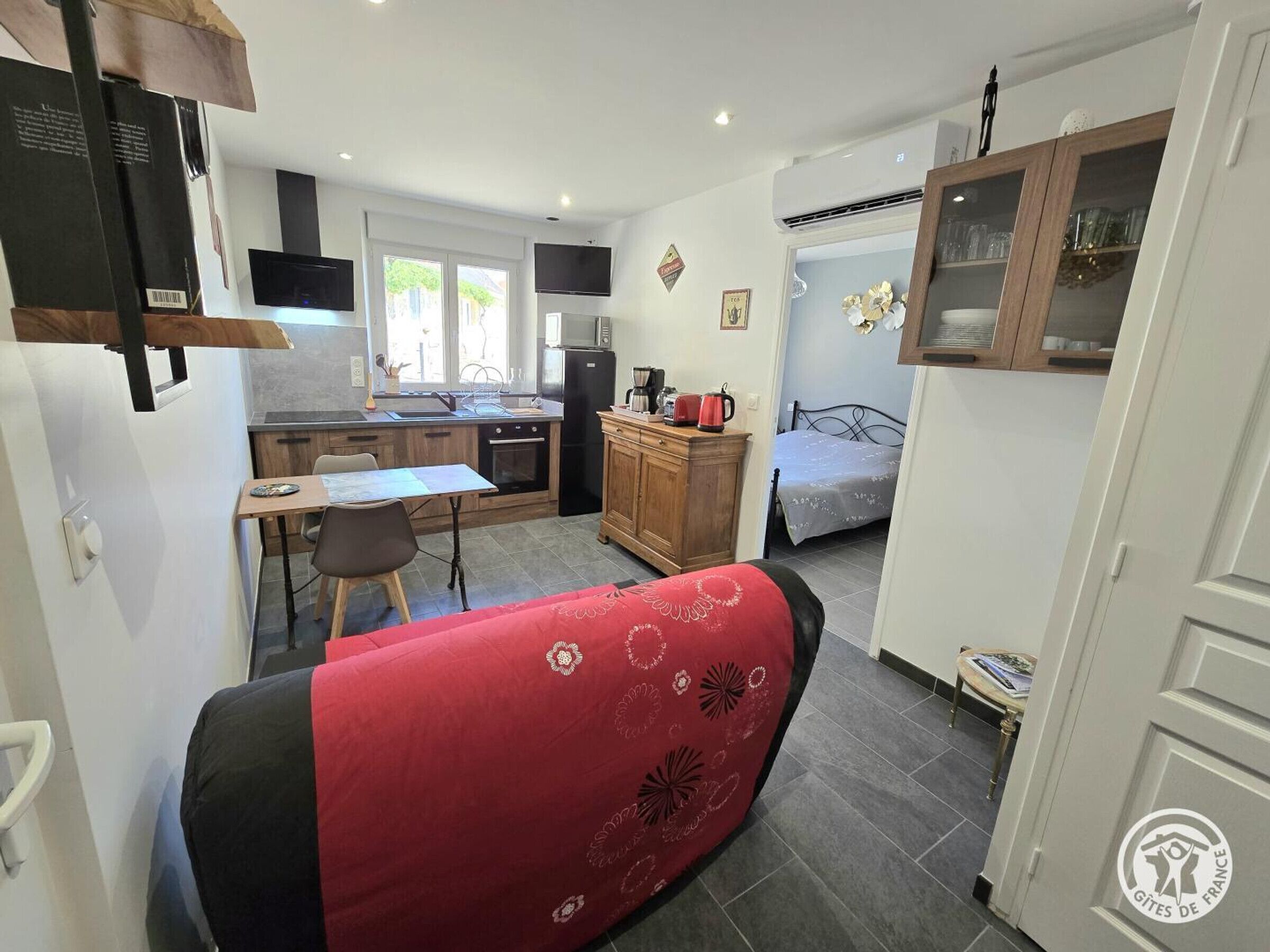 A compact kitchen with a dining area, a sofa, and a bed in a small room.