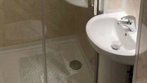 Een badkamer met een douchecabine van glas, een wit wastafelmeubel en een spiegel.