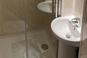 A bathroom with a glass shower enclosure, a white sink, and a mirror. - Brighton Bliss - Stylish Studio cosy on 1st floor (Brighton)