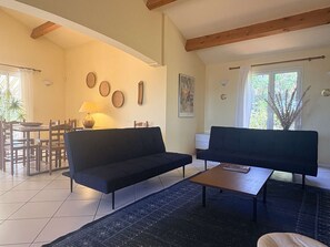 Ein Wohnzimmer mit zwei Sofas, einem Couchtisch, einem Esstisch mit Stühlen, einer Lampe und einem Bild an der Wand.