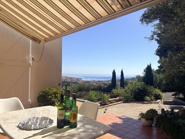 Eine Terrasse mit Tisch, Stühlen und alkoholischen Getränken.