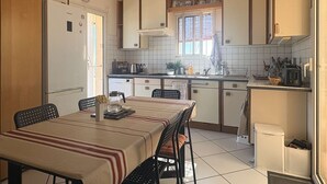 Eine kleine Küche mit Esstisch, Stühlen, Kühlschrank, Spüle und Schränken.