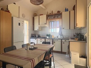 Eine kleine Küche mit Esstisch, Stühlen, Kühlschrank, Spüle und Schränken.