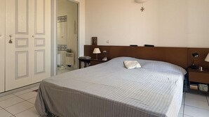 Ein Schlafzimmer mit einem Bett, Nachttischen, einer Wandlampe und einer Tür mit einer dekorativen Griff.