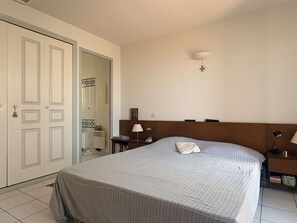 Ein Schlafzimmer mit einem Bett, Nachttischen, einer Wandlampe und einer Tür mit einer dekorativen Griff.