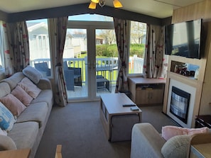 Ein gemütliches Wohnzimmer mit einer Couch, einem Couchtisch, einem Fernseher und einem Kamin.