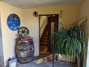 Ein Flur mit einem Holzfass, einem Willkommensschild, einer Treppe und einer großen Kübelpflanze.