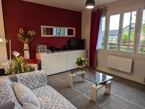 Ein modernes Wohnzimmer mit einer Couch, einem Glastisch, einem Fernseher und einer roten Wand.