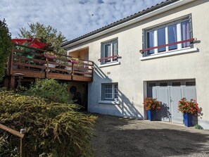 Uma casa de dois andares com varanda, garagem e plantas em vasos.