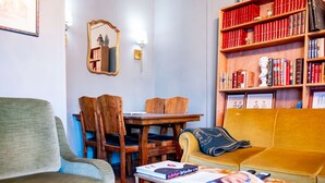Un salon comprenant un canapé, des fauteuils, une table basse, une bibliothèque et une table à manger.