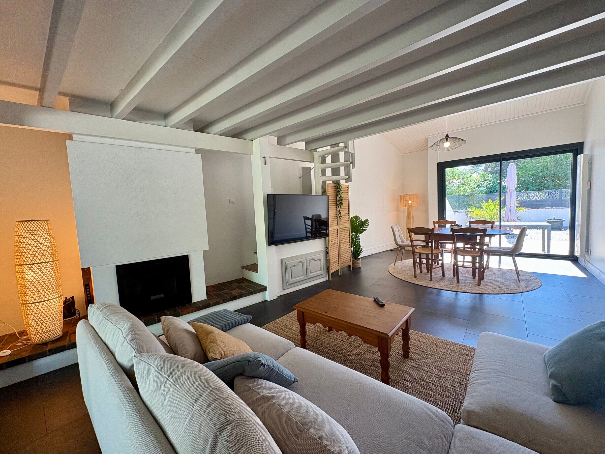 Ein modernes Wohnzimmer mit Kamin, Fernseher, Sofa und Essbereich.