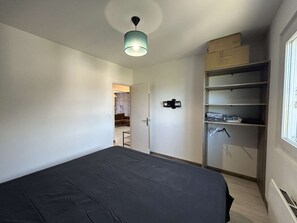 Ein Schlafzimmer mit einem Bett, einem Kleiderschrank und einer Tür zu einem anderen Raum.