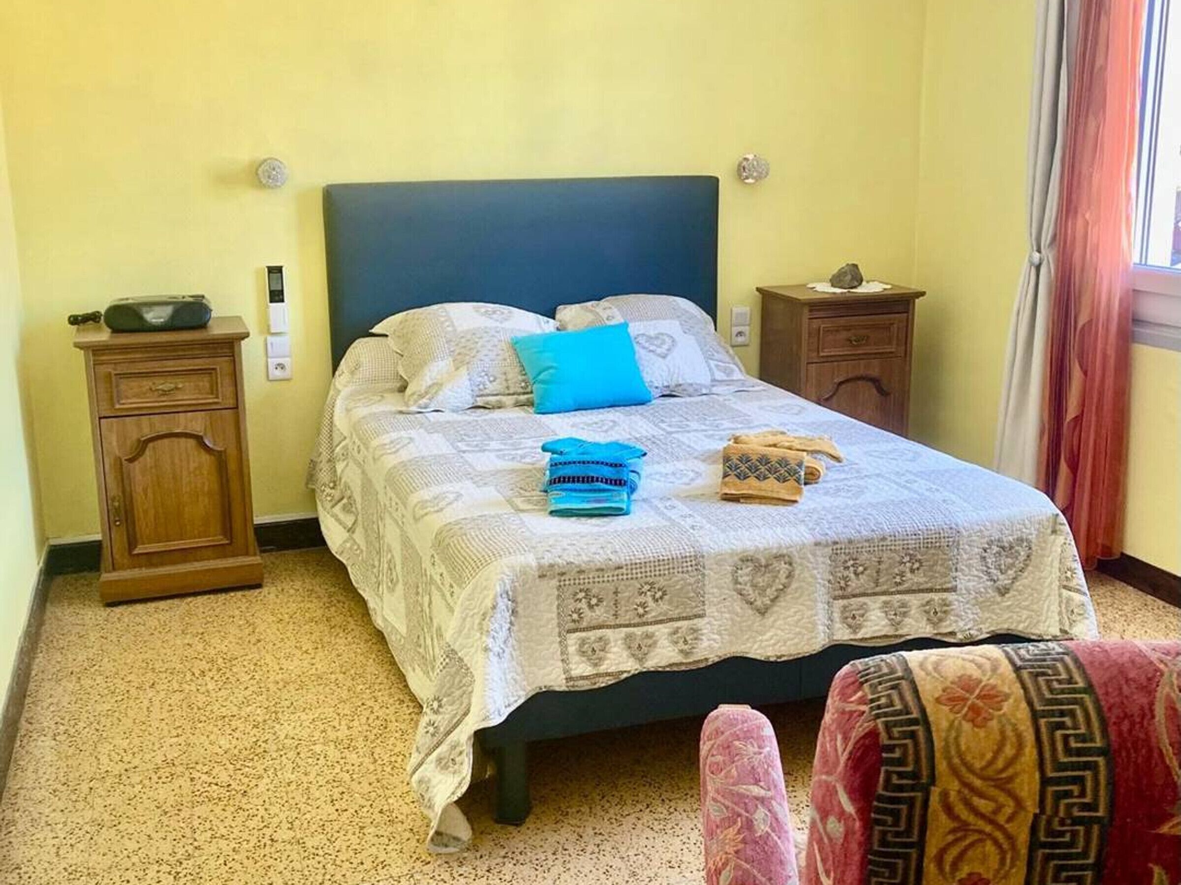 A bedroom with a bed, a nightstand, a dresser, and a window with curtains.