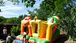 Eine aufblasbare Spielkonstruktion in einem Garten mit einem Picknicktisch und einem Schuppen im Hintergrund.