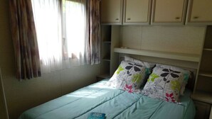 Ein Schlafzimmer mit einem Bett, Kissen, einem Buch und einem Fenster mit Vorhängen.