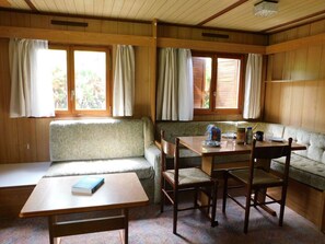 A cozy cabin interior with a dining table, two wooden chairs, a bench, and a sofa. - Cozy mobile home - 4 guests (Vesseaux)