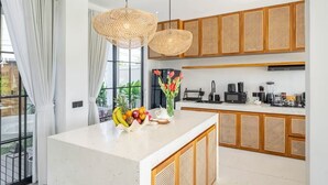 Een moderne keuken met een wit aanrecht, houten kastjes en een fruitschaal.
