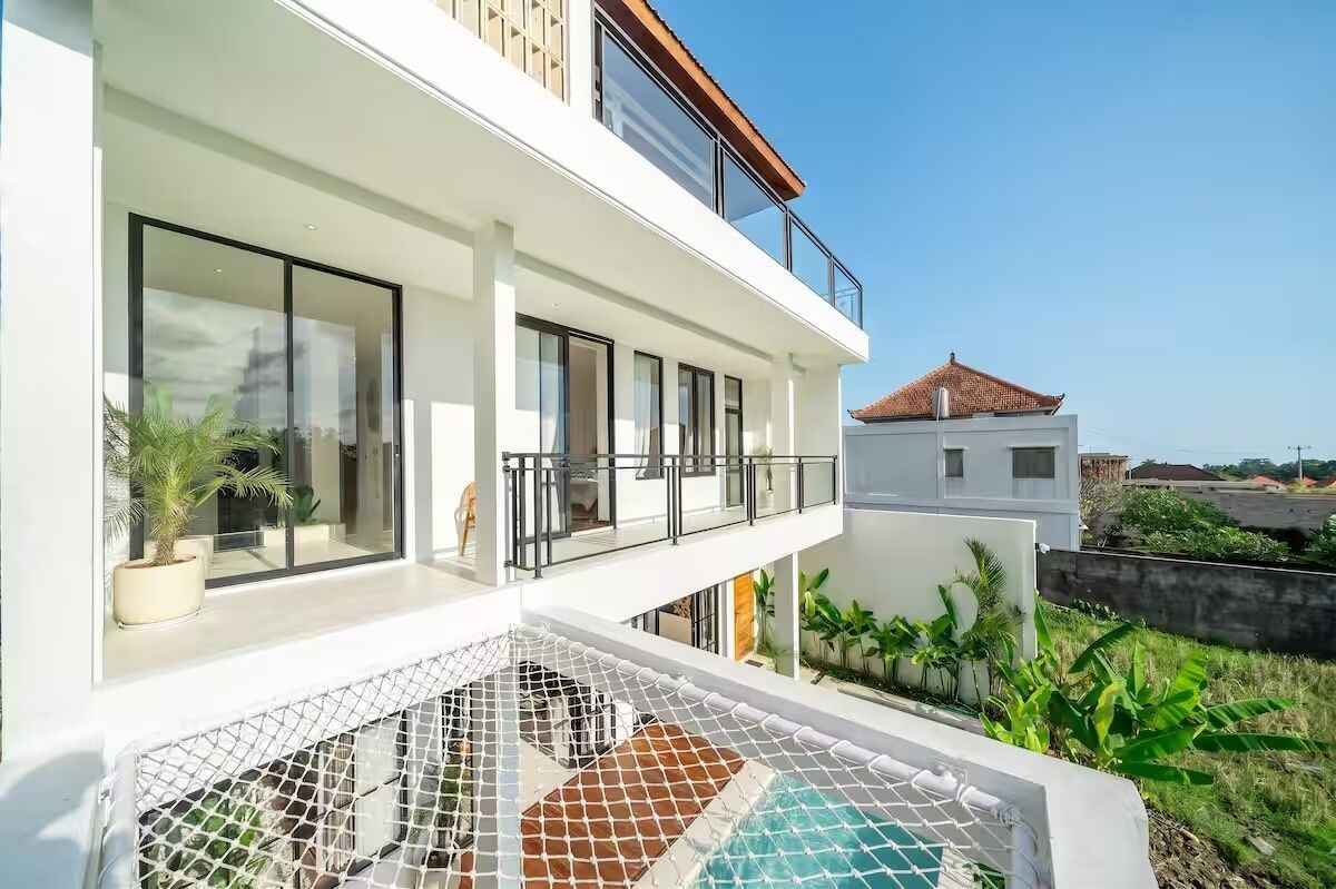 Ein modernes, zweistöckiges Gebäude mit großen Fenstern, einem Balkon und einem Poolbereich.