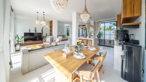 Een moderne keuken met een eethoek, houten kastjes en hangende lampen.