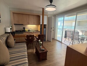 Eine moderne Wohnung mit Küche, Essbereich und einem Balkon mit Gartenmöbeln.
