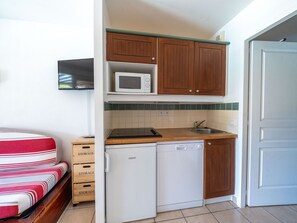 Eine kleine Küche mit Mikrowelle, Geschirrspüler und Holzschränken.