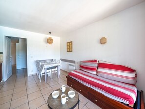 Ein kleines Zimmer mit einem Bett, einem Esstisch und einem kleinen runden Tisch mit Tassen.