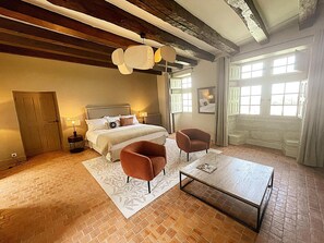 A bedroom with a bed, two armchairs, a coffee table, a fireplace, and a large window. - Charming cottage in Candes-St-Martin - 8 guests (Candes-Saint-Martin)