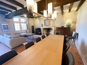A room with a wooden dining table, sofas, a fireplace, and hanging light fixtures. - Charming cottage in Candes-St-Martin - 8 guests (Candes-Saint-Martin)