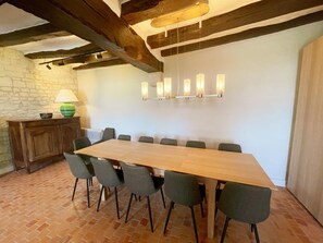 Un espace repas comprenant une longue table en bois, six chaises, une lampe et un luminaire fixé au mur.