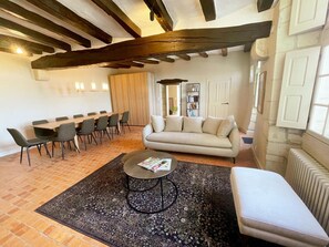 Una sala de estar con sofá, mesa de centro y comedor con sillas.