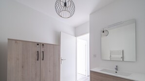 Ein modernes Badezimmer mit einem Holzschrank, einem weißen Waschbecken und einem großen Spiegel.