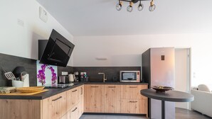 Eine moderne Küche mit Holzausstattung, einer Mikrowelle, einem Wasserkocher und einem Flachbildfernseher.