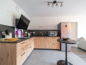 A modern kitchen with wooden cabinets, a microwave, a kettle, and a flat-screen TV. - Apartment city center, balcony - 4 guests (Parentis-en-Born)