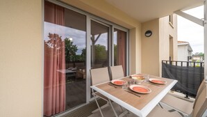 Ein Balkon mit Tisch für zwei Personen, einer Schiebeglastür und Blick ins Freie.