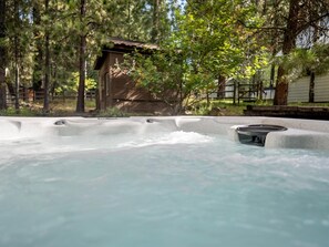 Un bain à remous entouré d’arbres et une structure en bois.