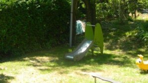 Ein Spielplatz mit Rutsche, einer gelben Schaukel und einem kleinen gelben Spielzeug.