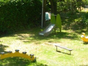 Ein Spielplatz mit Rutsche, einer gelben Schaukel und einem kleinen gelben Spielzeug.