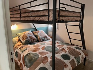A bunk bed with a patterned bedspread, a bedside lamp, and a wall-mounted power outlet. - T3 with AC, sea view, parking - 6 guests (Gruissan)