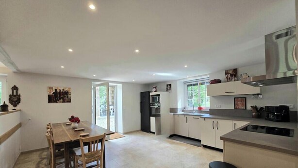 A modern kitchen with a dining area, large windows, and a central island. - Country house, private parking - 8 guests (Doissat)