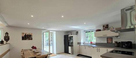 A modern kitchen with a dining area, large windows, and a central island.