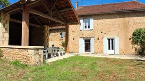 A stone house with a covered patio, a stone wall, and a small garden. - Country house, private parking - 8 guests (Doissat)