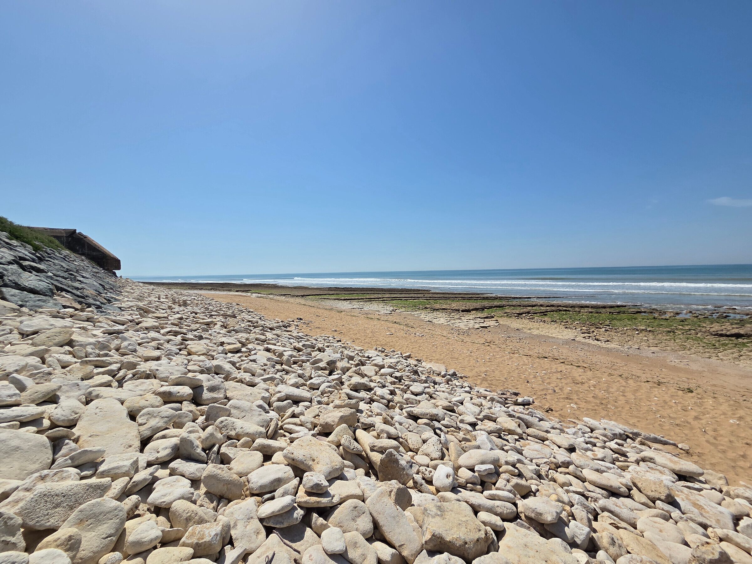 Ein felsiger Strand unter wolkenlosem Himmel.
