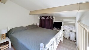 Et soveværelse med seng, sengebord, lampe og et vindue med gardiner.