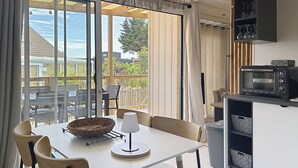 A dining area with a table, chairs, a lamp, a basket, and a microwave. - Beach house with AC - 6 guests (Saint-Pair-sur-Mer)